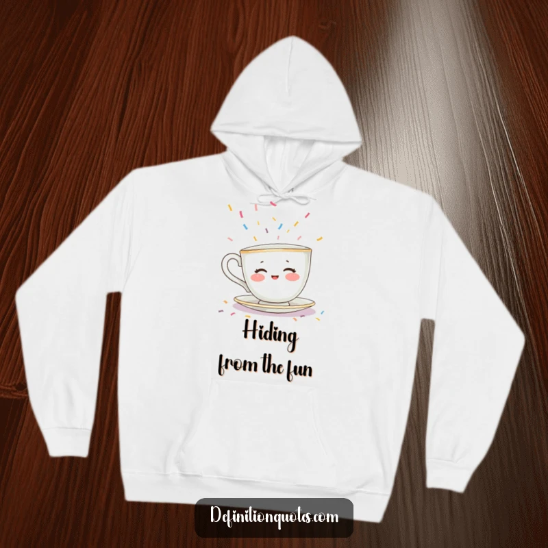 Funny hoodie depicting a shy teacup character with rosy cheeks hiding from falling confetti, a warm and humorous introvert gift.